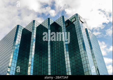 Niedriger Blick auf das moderne, moderne Glasgebäude gegen den blauen Himmel mit weißen Wolken Stockfoto