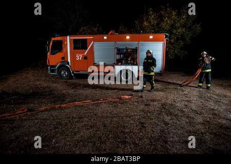 Feuerwehr Mannschaft in Uniform mit Schutzhelmen Löschen eines Brandes im Bereich Stockfoto