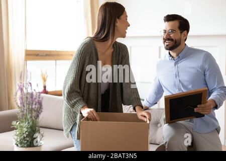 Überglücklich junge Ehepaare, die Gegenstände aus Kartons auspacken. Stockfoto