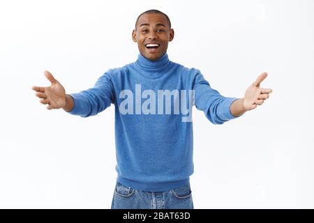 Willkommen, schön in Bis zum nächsten Mal. Portrait von freundlichen, glücklich und fröhlich lächelnden afroamerikanischen Mann einladenden Freund kommen in, strecken die Hände seitwärts und Stockfoto
