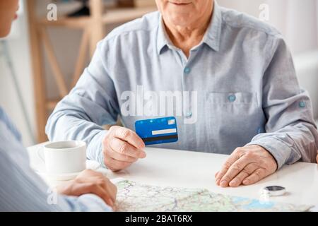 Reisebüro im Büro, der mit einem leitenden Kunden mit Debitkarte sitzt und die Zahlung aus nächster Nähe diskutiert Stockfoto