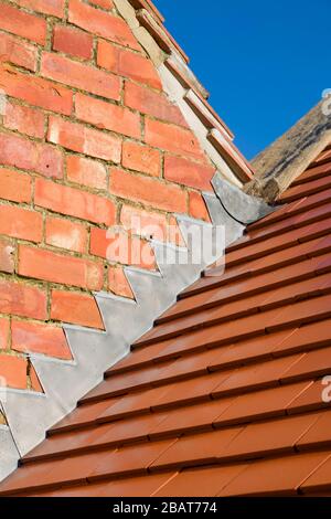Neue einfarbige rote Tonziegel und bleiblitzende Details auf einem Satteldach in Großbritannien Stockfoto