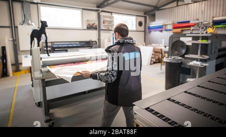 Der Bediener des Druckmaschinenherstellers arbeitet in der großen digitalen Druckmaschinenhalle und im Druckereibüro mit vielen verschiedenen Maschinentypen Stockfoto