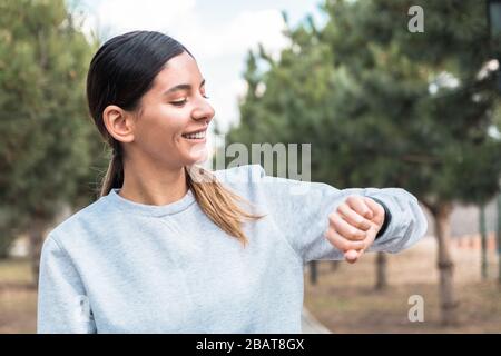 Fröhliche junge Frau, die ihre Vitalindikatoren auf dem intelligenten Fitnessband überwacht. Halten Sie Ihren Körper in guter Form Stockfoto