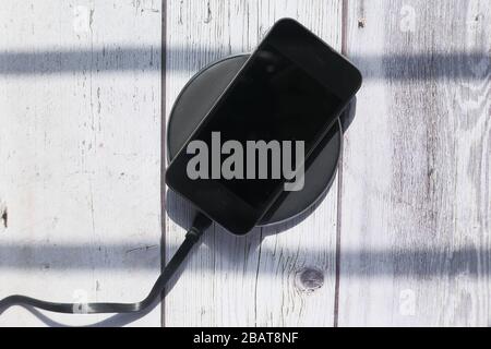 Draufsicht über das Aufladen des Smartphones auf dem Tisch. Stockfoto