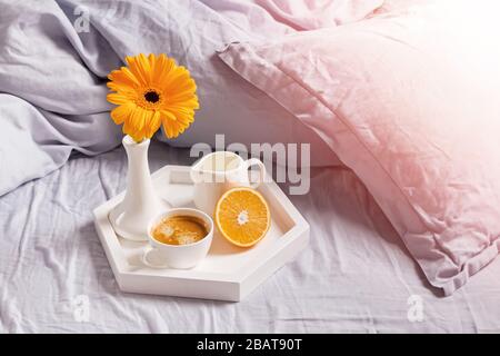 Tablett mit Kaffee, verzierten Blumen und Blumen auf dem Bett Stockfoto