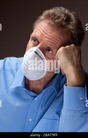 Besorgter älterer Mann mit chirurgischer Maske bleibt wegen Quarantäne der Kovid-19 zu Hause Stockfoto