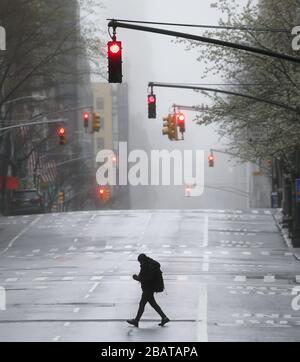 New York, USA. März 2020. Wenn rote Lichter erscheinen, überquert ein Mann die Lexington Avenue, wo Fußgänger- und Autoverkehr am Sonntag, 29. März 2020, in New York City fast nicht mehr vorhanden sind. Am Samstag veröffentlichten die Centers for Disease Control and Protection eine 14-tägige Reiseberatung für New York, New Jersey und Connecticut. Die Anzahl der bestätigten COVID-19-Fälle im Dreiländergebiet hat 65.000 überschritten und mindestens 901 Menschen sind tot bestätigt. Stockfoto