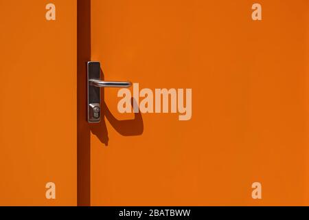 Tür aus hellorangefarbenem Metall mit Griffnähe. Modernes Äußeres Stockfoto