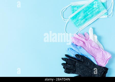 Mehrfarbige latexchirurgische Handschuhe und chirurgische Masken auf blauem Hintergrund Draufsicht. Virenschutzkonzept. Stockfoto