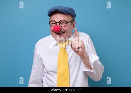 Zufriedener älterer Clown Mann mit roter Nase zeigt Zeigefinger Nach oben Stockfoto