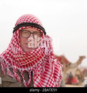 Ein Tourist, der eine traditionelle Nahost-Adresse trägt, während er das Giza-Plateau in Kairo, Ägypten besucht. Stockfoto