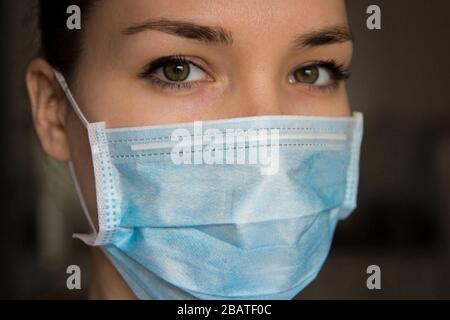 Frau mit Schutzmaske gegen Coronavirus auf dunklem Hintergrund Stockfoto