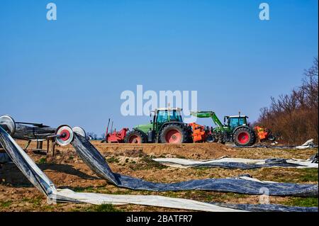 Brandenburg, Deutschland - 28. März 2020: Blick auf Traktoren und Maschinen, die bereit sind, in Deutschland ein Spargelfeld für den Anbau vorzubereiten. Stockfoto