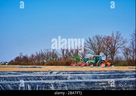 Brandenburg, Deutschland - 28. März 2020: Blick auf Traktoren und Maschinen, die bereit sind, in Deutschland ein Spargelfeld für den Anbau vorzubereiten. Stockfoto