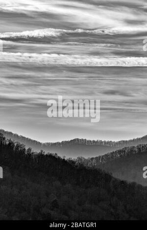 Kondensstreifen und Wolken machen interessante Designs am Himmel am Tanbark Ridge Overlook auf dem Blue Ridge Parkway in Asheville, NC, USA. Stockfoto