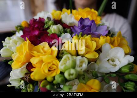 Geringe Schärfentiefe (selektiver Fokus) mit einer Frau, die einen frischen Blumenstrauß Freesias hält. Stockfoto