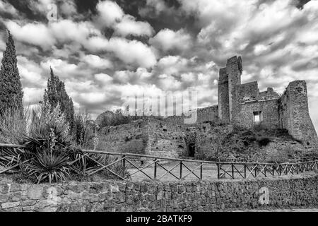 Atemberaubender Schwarz-Weiß-Blick auf die Ruinen der Rocca Aldobrandesca von Sovana, Grosseto, Toskana, Italien, gegen einen dramatischen Himmel Stockfoto