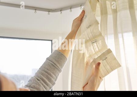 Nahaufnahme der Frau hängende Vorhänge mit Metallhaken an der Decke. Stockfoto