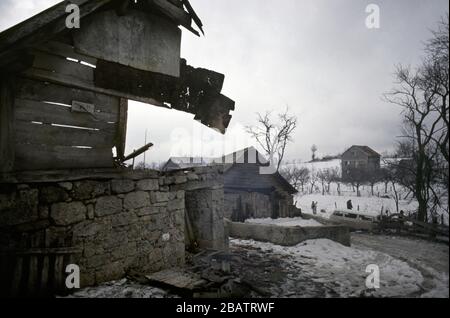 Januar 1994 während des Krieges in Zentralbosnien: Noch immer zerschlägende Häuser, während Soldaten der Rama Brigade der HVO durch das bosnisch-muslimische Dorf hier spazieren, das zwei Tage zuvor gefangen genommen wurde. Stockfoto