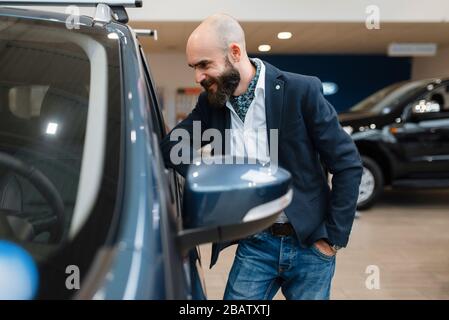 Lächelnder Mann posiert im Autohaus im Auto Stockfoto