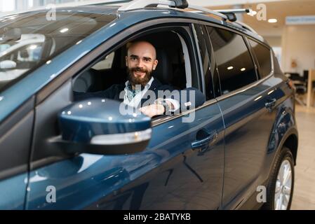 Lächelnder Mann posiert im Auto, Autohaus Stockfoto