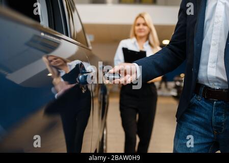 Mann und Verkäuferin wählen Auto im Autohaus Stockfoto