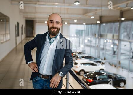 Glücklicher Geschäftsmann posiert im Autohaus Stockfoto