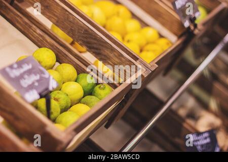 Nahaufnahme von Kisten mit verschiedenen Früchten im Lebensmittelgeschäft. Limes, Orangen und Zitronen in Holzkisten am Obststall am Markt. Nähren, gesundes Lifestyl Stockfoto