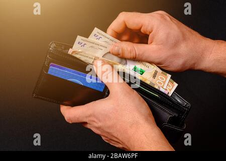 Nahaufnahme in den Händen der Brieftasche eines Mannes, wenn er eine 500-Hrywny-Banknote auszieht. Stockfoto