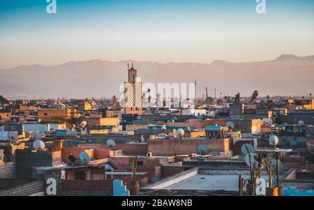 Panoramablick auf Marrakesch Medina und das schneebedeckte Atlasgebirge in Marokko. Blick auf die Dächer von Marrakesch in der Nähe des Stadtzentrums Stockfoto