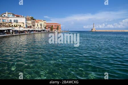 Blick auf den Hafen von Chania und den Leuchtturm, umgeben von klarem Wasser, zweitgrößte Stadt der Insel Crete, Griechenland. Stockfoto