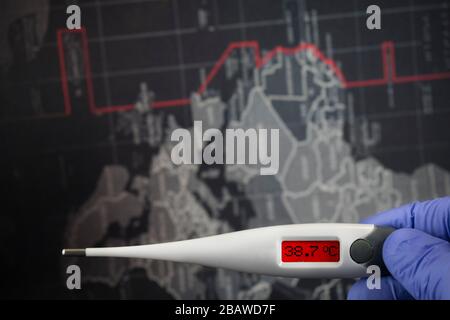 Anzeige von 38,7 C Celsius vor dunklem Hintergrund der Weltkarte. Pfadauswahl inbegriffen.Arzthand mit blauen medizinischen Handschuhen hält digitales Thermometer Stockfoto