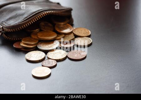 Ledertasche mit einigen Euromünzen auf schwarzem Hintergrund, Geldsparkonzept. Platz für Text Stockfoto