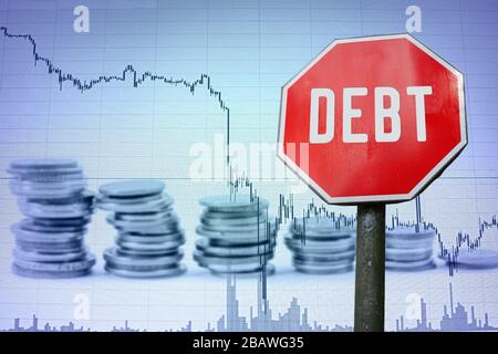 Schuldenzeichen auf dem wirtschaftlichen Hintergrund - Grafik und Münzen. Finanzunfall in der Weltwirtschaft wegen Coronavirus. Weltwirtschaftskrise, Rezession Stockfoto