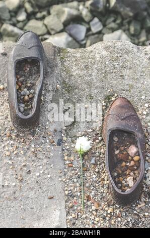 Budapest, Ungarn - 6. November 2019: Schuhe an der Donau-Bank. Denkmal zur Ehrung der Juden, die im zweiten Weltkrieg von Faschisten getötet wurden Eisenschuhe mit Blume von oben fotografiert. Stockfoto