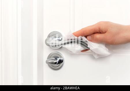 Eine Person, die den Türgriff säubert, um die Ausbreitung von Keimen, Bakterien und Corona-Viren zu verhindern. Stockfoto