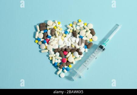 Pillen, die in Herzform auf blauem Hintergrund liegen. Verschiedene Pillen zusammen. Stockfoto