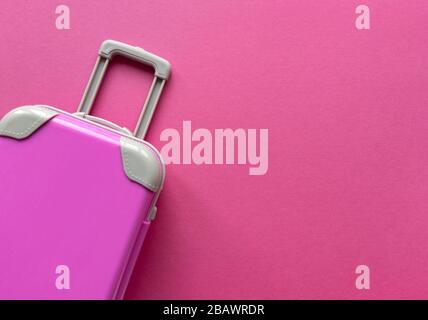 Rosafarbener Kunststoffkoffer auf Pastellpapier Hintergrund.Reisekonzept Urlaub Sommerabenteuer Reise. Flach lag mit einer einfachen Sache. Stock-Foto. Stockfoto