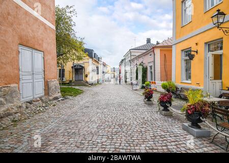 Eine kleine, malerische und farbenfrohe Straße mit Kopfsteinpflaster mit Geschäften und Cafés im mittelalterlichen Dorf Porvoo, Finnland. Stockfoto