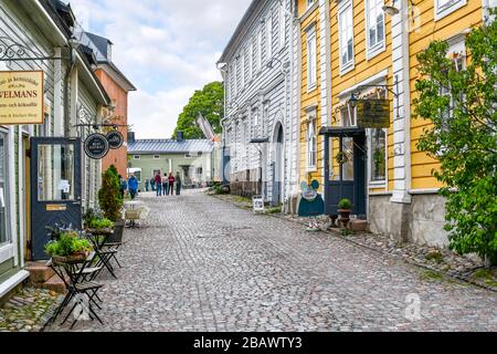 Eine kleine, malerische und farbenfrohe Straße mit Kopfsteinpflaster mit Geschäften und Cafés im mittelalterlichen Dorf Porvoo, Finnland. Stockfoto