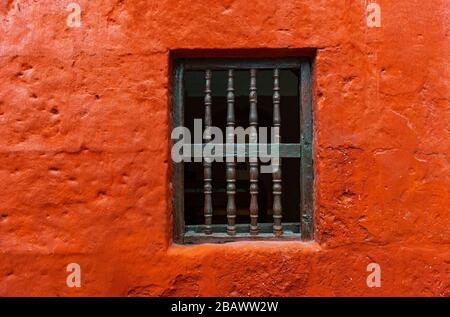 Fenster gegen eine orangefarbene Putzfassade im Kloster Santa Catalina von Arequipa, Peru. Stockfoto