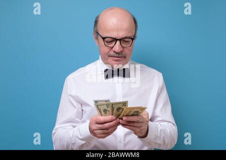 Hispanischer männlicher Rentner in Gläsern mit Gelddollar Stockfoto