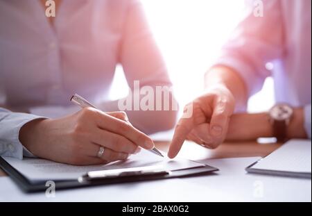 Geschäftsleute, die einen Vertrag aushandeln. Menschliche Hände, die mit Dokumenten am Schreibtisch arbeiten und einen Vertrag unterzeichnen. Stockfoto