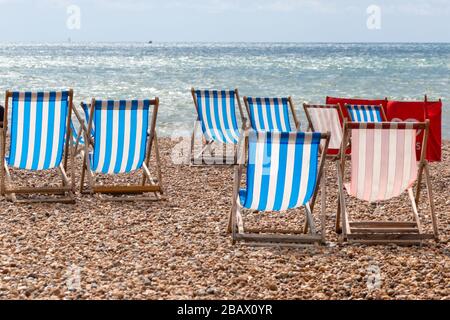 Farbenfroh gestreifte liegen zu mieten am Kieselstrand in Brighton, East Sussex, England Stockfoto