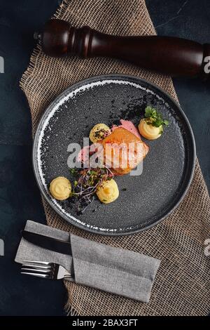 Gebratenes Schweinekotelett, Kartoffelpüree auf einem schönen Teller, serviert auf dem Tisch. Food Foto, Kopierbereich, grauer Hintergrund. Stockfoto