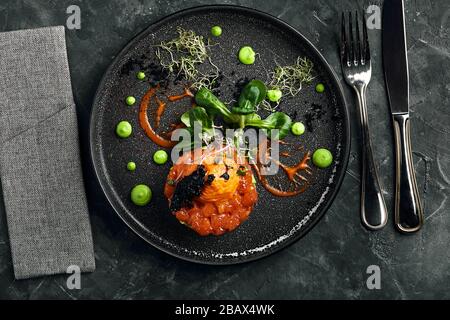 Lachs-Tartare mit Avocado und Gemüse, ein wunderschönes Layout vom Koch, ein wunderschöner malohot - Marmorhintergrund. Food Foto, Werbebanner Stockfoto