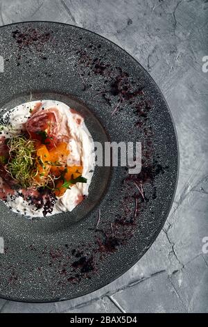 Italienische Käse Burrata Mozzarella und Stracatella wird auf einer Platte mit Paprika, Tomaten und frischen Rucola, frisch gemahlenem Pfeffer und serviert Stockfoto