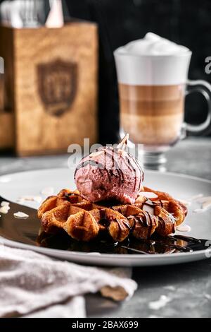 Wiener Waffeln mit Eis und Kaffee. Wunderschönes Dessertbild mit Lettenkaffee. Dessertkonzept, süßes Leben. Lebensmittelfoto, Kopierbereich, grau Stockfoto