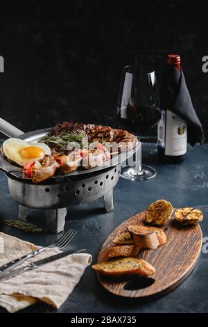 Grillplatte. Verschiedene leckere gegrilltes Fleisch mit Gemüse. Gegrilltes gemischtes Fleisch mit Pfeffersauce und Gemüse. Die Hände des Küchenchefs verteilen Fleisch Stockfoto